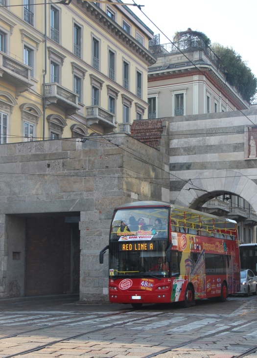 A red double-decker sightseeing bus in the centre of Milan