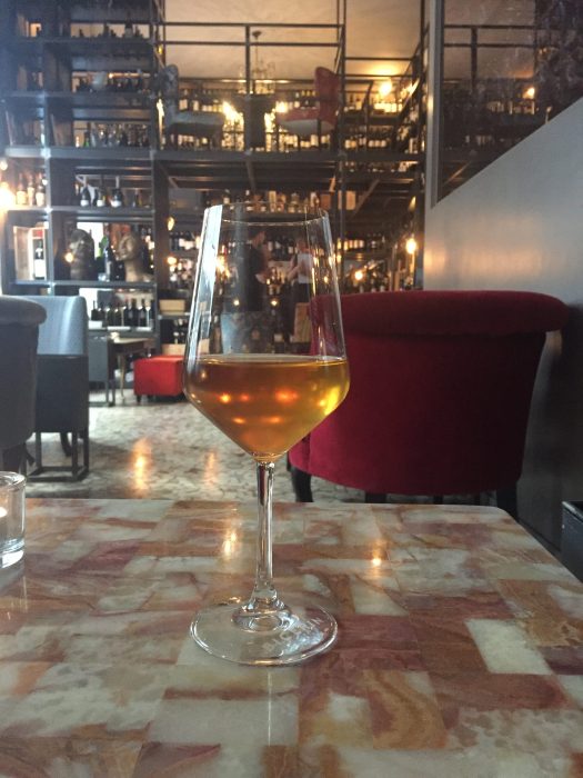 A glass of orange wine at a wine bar in Porta Vnezia, Milan